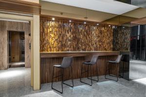 um bar com três bancos em frente a uma parede de madeira em JIASHITE HOTEL em Taoyuan