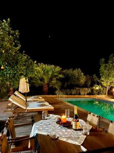 uma mesa com uma garrafa de vinho ao lado de uma piscina em Villa Domenico em Vryses