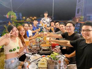 a group of people sitting around a table with food at Domik Homestay - Cát Bà in Cat Ba +46 photos