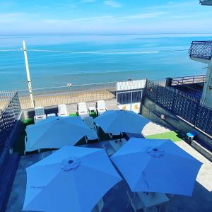 balcone con ombrelloni e sedie blu e oceano di Castello di Sabbia a Trabia