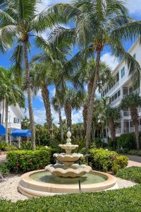a fountain in front of a building with palm trees at Marco Island Condo with Shared Pool and Hot Tub! in Marco Island