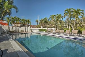 a large swimming pool with chairs and palm trees at Marco Island Condo with Shared Pool and Hot Tub! in Marco Island