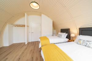 two beds in a room with an arched ceiling at Cultybraggan Hut 37 in Comrie