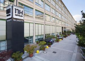 een groot gebouw met auto's geparkeerd voor het bij NH Torino Lingotto Congress in Turijn