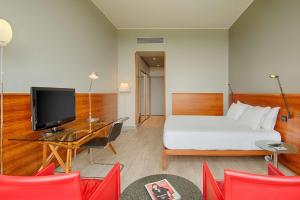 a hotel room with a bed and a desk with a television at NH Torino Lingotto Congress in Turin