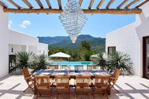 un patio con mesa de comedor y sillas y piscina en Exclusive Luxury Villa South Facing Vista De Muntanya 6 Bedrooms A Few Minutes Drive To The Beach San Jose, en Sant Josep de sa Talaia
