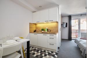 a kitchen with white cabinets and a sink and a bed at Villa Alpina in Szklarska Poręba