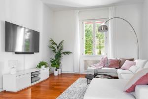 een witte woonkamer met een witte bank en een tv bij Specola Magical View Apartment in Padua