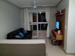 a living room with a couch and a television at Edf Gil Nogueira-Praia Morro-Guarapari-3º Andar-APTO FTE-SOL MANHA-Piscina-Sauna-02 quartos com Ar -TV Tela Plana-Wi-Fi-Varanda Gourmet -Tela de Proteção - Purificador Água-Airfray-Dois elevadores-01 Garagem-Portaria 24 horas-50 mts da Praia do Morro in Guarapari