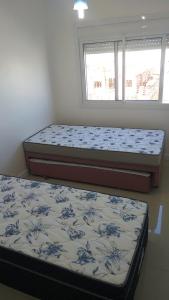 two beds sitting in a bedroom with a window at APARTAMENTO ACQUA DI FIRENZE CAPAO in Capão da Canoa