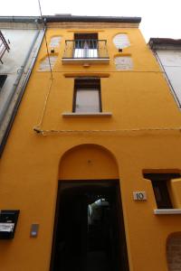 ein gelbes Gebäude mit einer Tür und einem Balkon in der Unterkunft PETITE MAISON in Lanciano