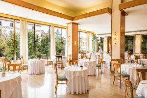 un ristorante con tavoli e sedie bianchi e finestre di HOTIDAY Hotel Sorrento a Sorrento
