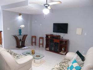 uma sala de estar com um sofá e uma televisão de ecrã plano em Casa completa em Peró! em Cabo Frio