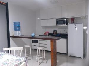 uma cozinha com um balcão, um frigorífico e bancos em Casa completa em Peró! em Cabo Frio