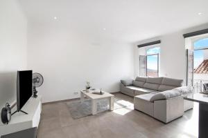 a white living room with a couch and a tv at Traditional 3 bedroom apartment in Alte