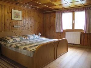 - une chambre avec un grand lit dans une pièce dotée de murs en bois dans l'établissement Landhaus Ossi, à Gaschurn