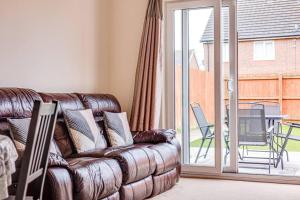 un sofá de cuero en una sala de estar con una puerta corredera de cristal en Cosy 2 Bedroom Home in Wigan, en Wigan