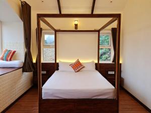 a four poster bed in a room with two windows at Sky Sketch in Kodaikānāl