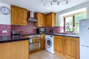 a kitchen with wooden cabinets and a washer and dryer at Saddle Cottage in Penzance