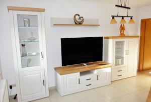 a living room with a tv and a white cabinet at Ferienwohnung Sternenkieker in Krummhörn