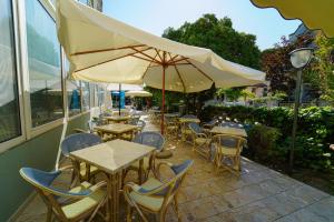 una cafetería al aire libre con mesas, sillas y sombrilla en Dasamo Hotel - Dada Hotels en Rímini
