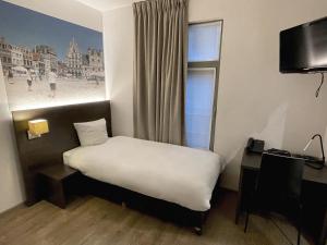 a bedroom with a bed and a window and a desk at 3 Paardekens - City Centre Hotel in Mechelen