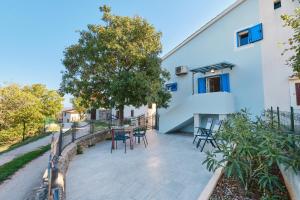 un patio con sillas y una mesa frente a un edificio en Domus Olivae en Nerezine