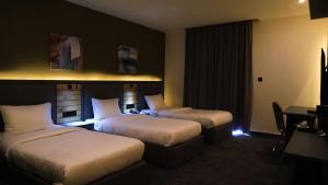 a hotel room with two beds and a desk at Aitch Boutique Hotel - an LIH Hotel in Madaba