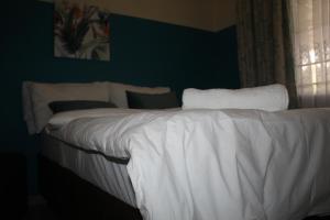 a white bed in a bedroom with a green wall at Sable Holiday Home in Hazyview