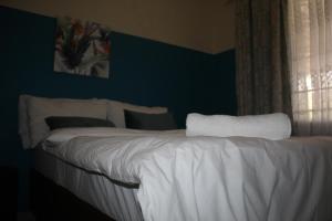 a bedroom with a bed with white sheets and a window at Sable Holiday Home in Hazyview