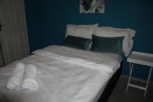 a bed with white sheets and pillows next to a table at Sable Holiday Home in Hazyview
