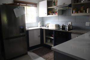 a kitchen with a stainless steel refrigerator and white cabinets at Sable Holiday Home in Hazyview