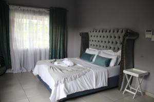 a bedroom with a large bed with green curtains at Sable Holiday Home in Hazyview