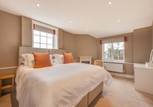 a bedroom with a large white bed with orange pillows at CowPasture Cottage in Felixstowe