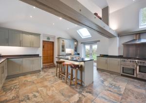 a large kitchen with white cabinets and a island with bar stools at CowPasture Cottage in Felixstowe