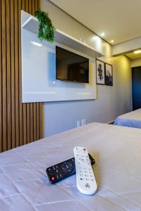 mando a distancia sentado en la parte superior de una cama con TV en Apart Hotel Centro de Brasília en Brasilia