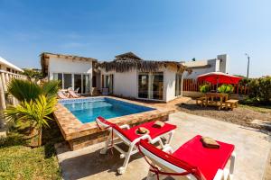 a house with a swimming pool and two red chairs at Casa Killa Vichayito in Vichayito