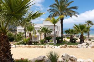 カステッランマーレ・デル・ゴルフォにあるLa Blanca Resort & Spaのヤシの木が植えられた浜辺の家