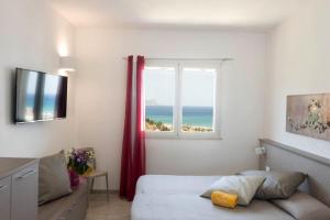 a bedroom with a bed and a window with the ocean at La Blanca Resort & Spa in Castellammare del Golfo