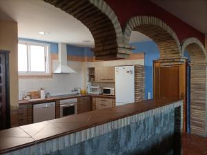 a kitchen with an archway and a white refrigerator at La Mejana in Malón