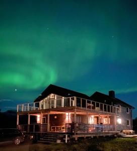 a house under the northern lights in the sky at In the heart of the Lyngen alps, Holmen i Lyngen in Lyngseidet