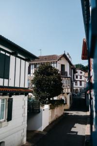 vistas a una calle con edificios y un árbol en Hôtel La Caravelle, en Ciboure