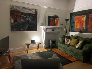 a living room with a green couch and a table at Airy Apartment Sefton Park in Liverpool