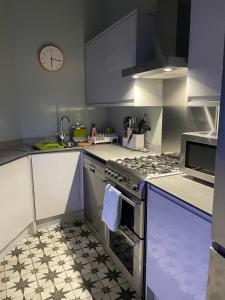 une cuisine avec une cuisinière et une horloge au mur dans l'établissement Airy Apartment Sefton Park, à Liverpool