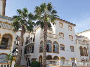 um edifício com palmeiras em frente em Sunlight Apartment - Molino Blanco - La Zenia em Playas de Orihuela