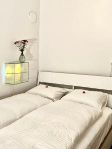 2 Betten mit weißer Bettwäsche und eine Vase mit Blumen in der Unterkunft Villa Bergruh in St. Gallen