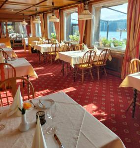 restauracja z białymi stołami, krzesłami i oknami w obiekcie Hotel Schiff am Schluchsee w mieście Schluchsee