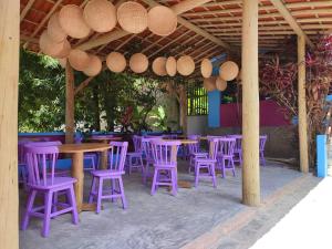 un groupe de tables et de chaises violettes sous un pavillon dans l'établissement Vila Anauá, à Japaratinga