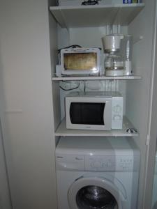 a kitchen with a microwave and a washing machine at A Deux Pas du Courant in Mimizan-Plage