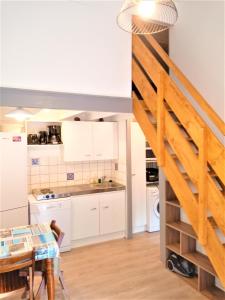 a kitchen with white cabinets and a wooden staircase at A Deux Pas du Courant in Mimizan-Plage